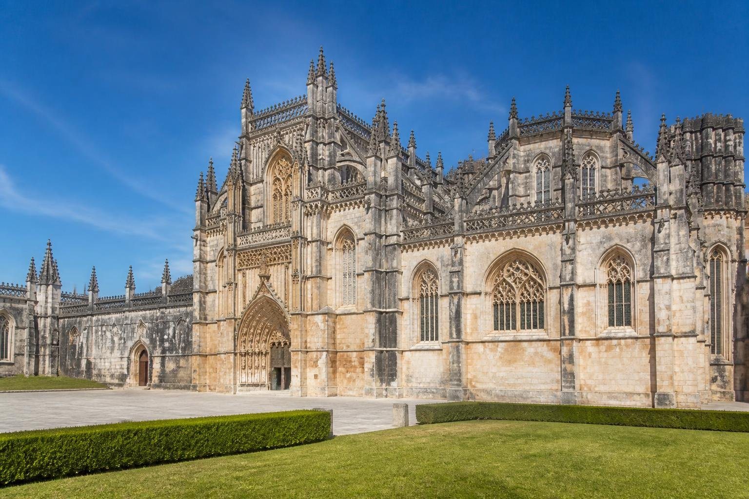 Vista do Mosteiro da Batalha com sua fachada imponente e detalhes arquitetônicos em um dia ensolarado.
